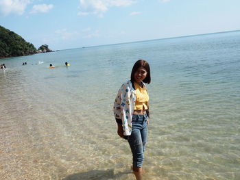 Full length of smiling woman standing on beach