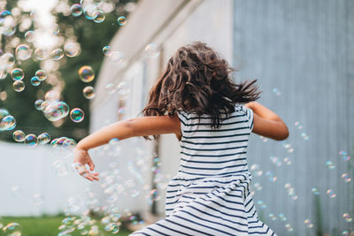 Diverse mixed race pre school age girl at home having fun playing with bubbles 