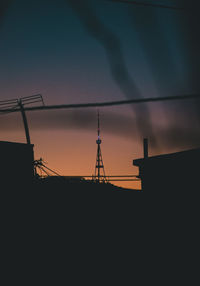 Low angle view of electricity pylon against sky during sunset