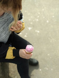 Low section of woman having ice cream on road