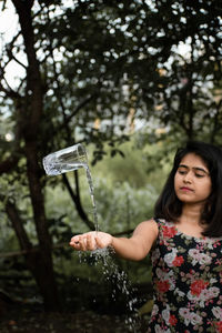 Digital composite image of drinking glass in mid-air by young woman on field