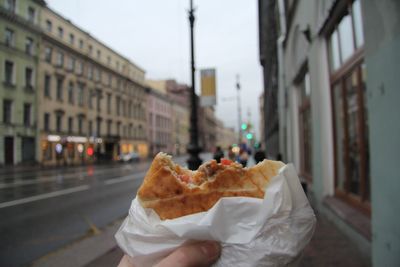 Close-up of hand holding food on footpath