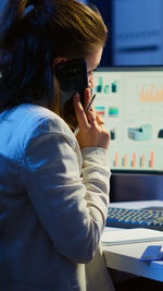 Side view of young woman using mobile phone in office