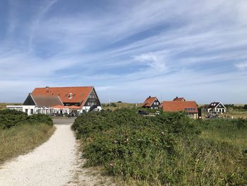 Scenic view of field by houses against sky