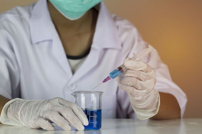 Midsection of woman doing scientific experiment at table