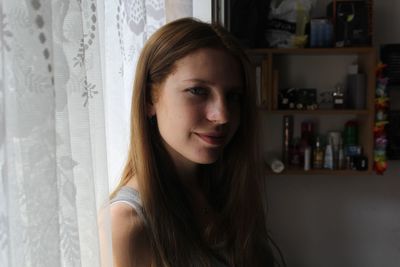 Portrait of smiling woman by curtains at home