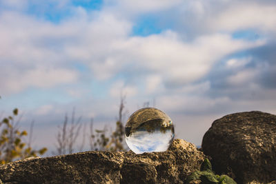 Low angle view of crystal ball on rock against sky