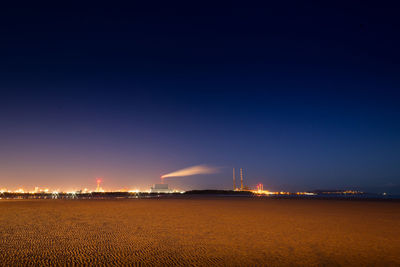 Illuminated factory against sky at night