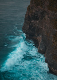 High angle view of sea waves splashing against rock formation