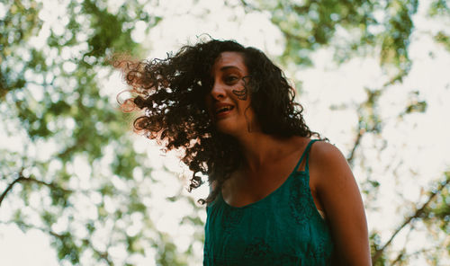 Portrait of young woman standing against trees