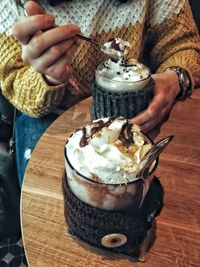 Midsection of person holding ice cream on table