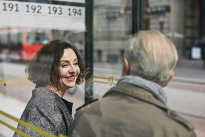 Smiling woman talking to man at bus stop
