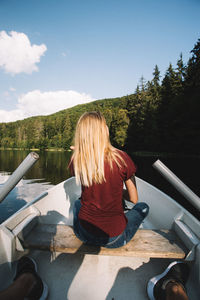 Rear view of woman sitting on mountain against sky