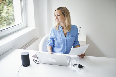 Woman using mobile phone while sitting on table