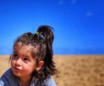 Cute girl at beach against blue sky