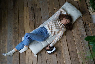 Relaxed millennial woman dreaming after using virtual reality interface, top view