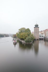 View of buildings by river against sky