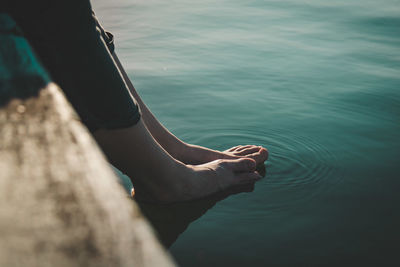 Low section of woman feet in water at lake