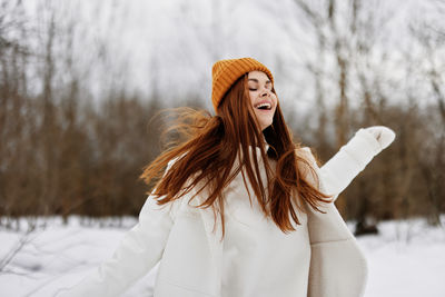 Portrait of young woman standing on snow covered field