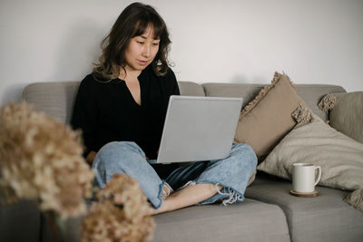 Businesswoman with cross-legged sitting on sofa with laptop
