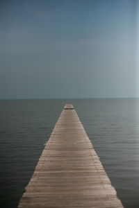 Wooden pier over sea against sky