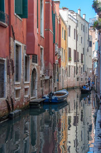 Boats moored in canal amidst buildings in city