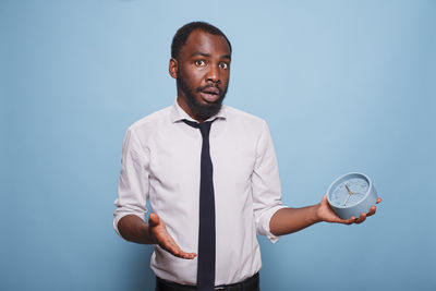 Portrait of young man standing against blue background