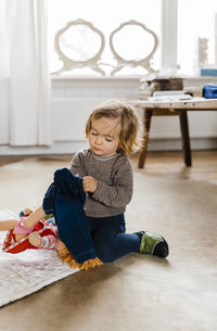 Cute girl wearing jacket while kneeling on floor at home