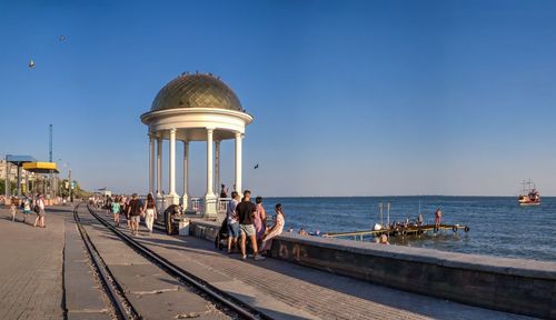 People at seaside against blue sky