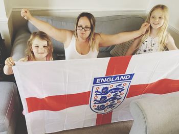 Portrait of woman with daughters holding english flag