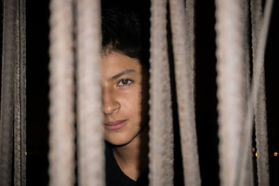 Portrait of young man seen through metallic rods at night