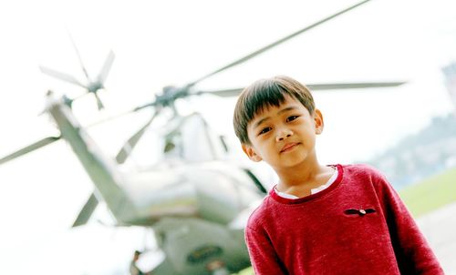 Close-up of boy standing against helicopter