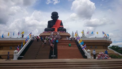 Low angle view of statues on staircase amidst buildings against sky