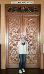 Portrait of young woman standing against wall