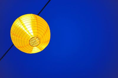 Low angle view of lantern hanging against clear blue sky