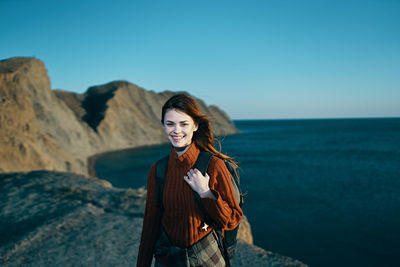 Young woman standing at sea shore against sky