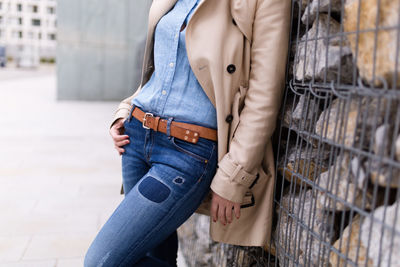 Midsection of woman wearing jeans standing by wall