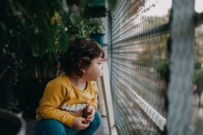 Girl looking away while sitting outdoors