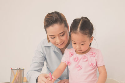 Mother assisting daughter drawing with crayon