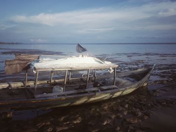 Boat moored on beach against sky