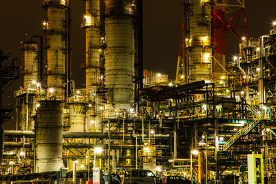 Low angle view of illuminated factory against sky at night