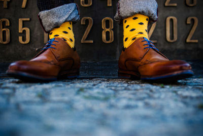 Low section of man wearing shoes and yellow socks standing on road