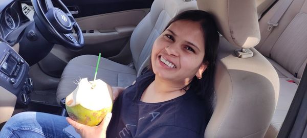 Portrait of smiling young woman sitting in car