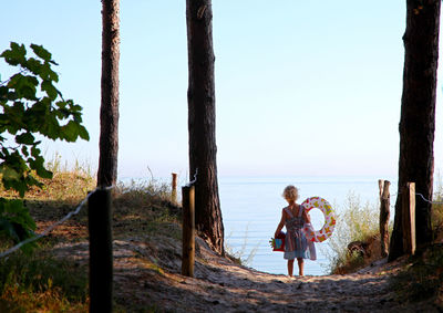 Girl standing on path to the beach  against sky