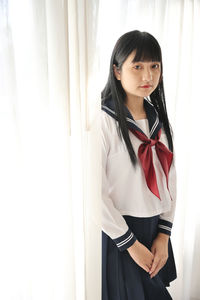 Portrait of young woman standing against wall
