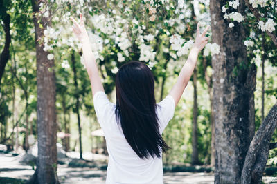 Rear view of woman standing on tree trunk