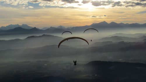 Low angle view of silhouette person paragliding against sky