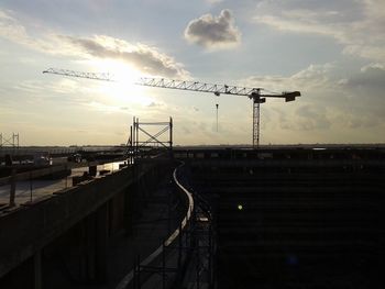 Cranes against sky at sunset