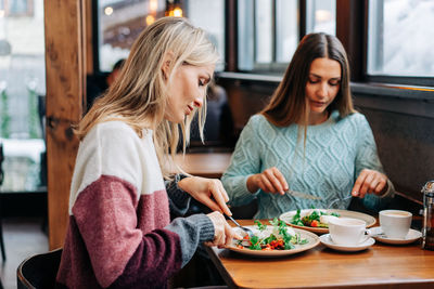 Two women eat european cuisine in a cozy restaurant in a ski resort.