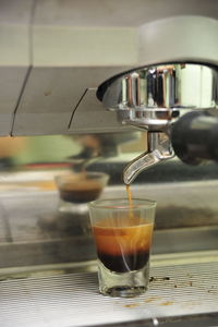 Close-up of coffee pouring in glass at cafe